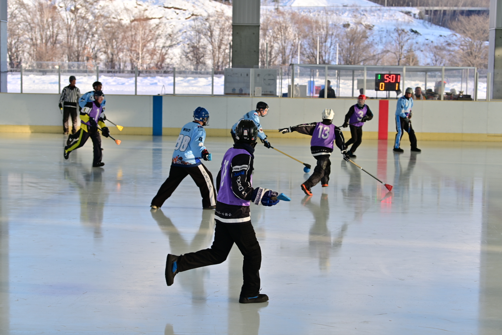 Wide-angle game action with scoreboard showing the time